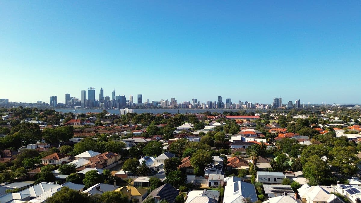 Aerial view of Perth city skyline and its surrounding suburban homes under a clear blue sky