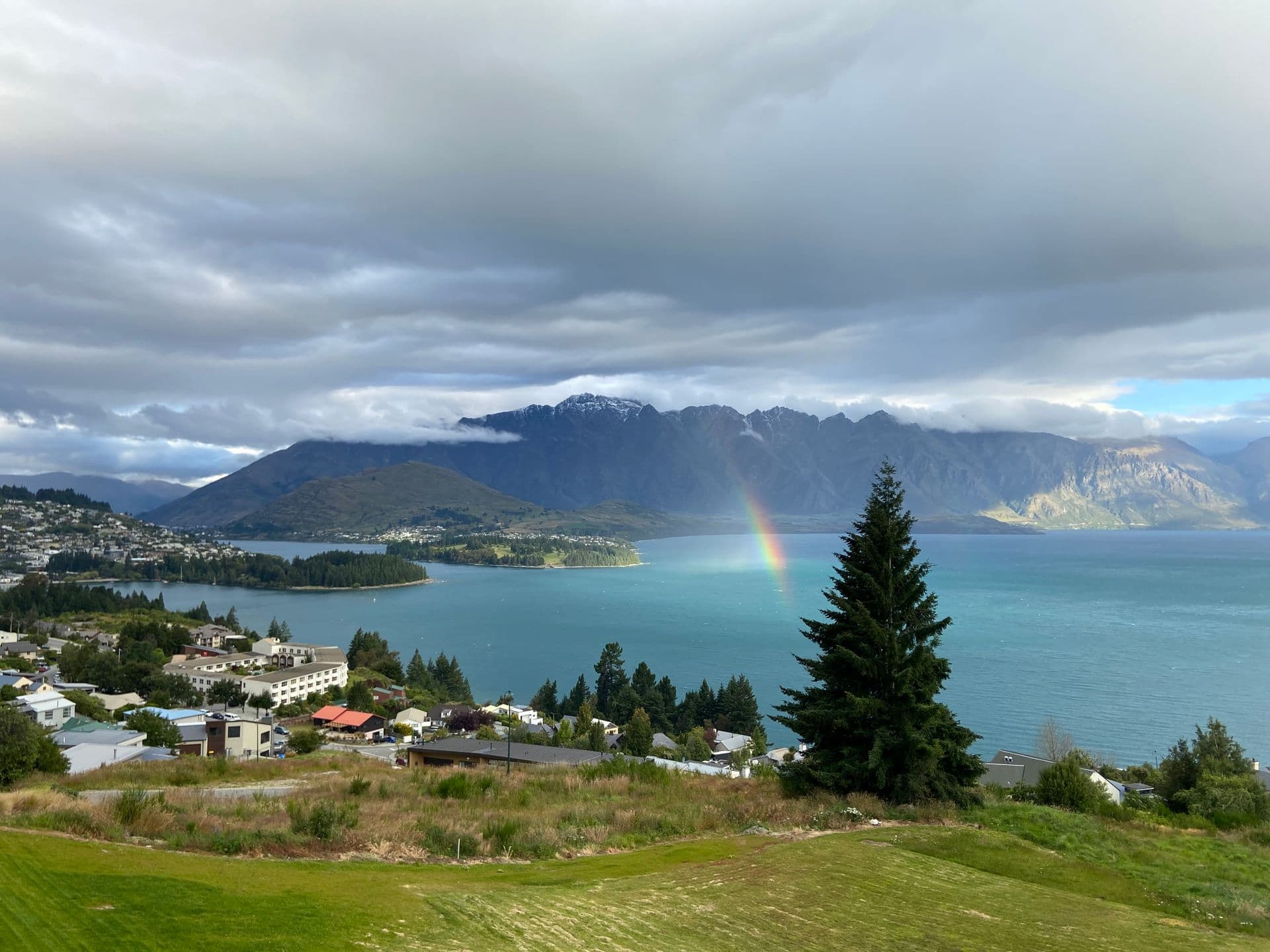 Aerial view of Lake Wakatipu and the Remarkables mountain range near Queenstown, New Zealand, with a rainbow over the water